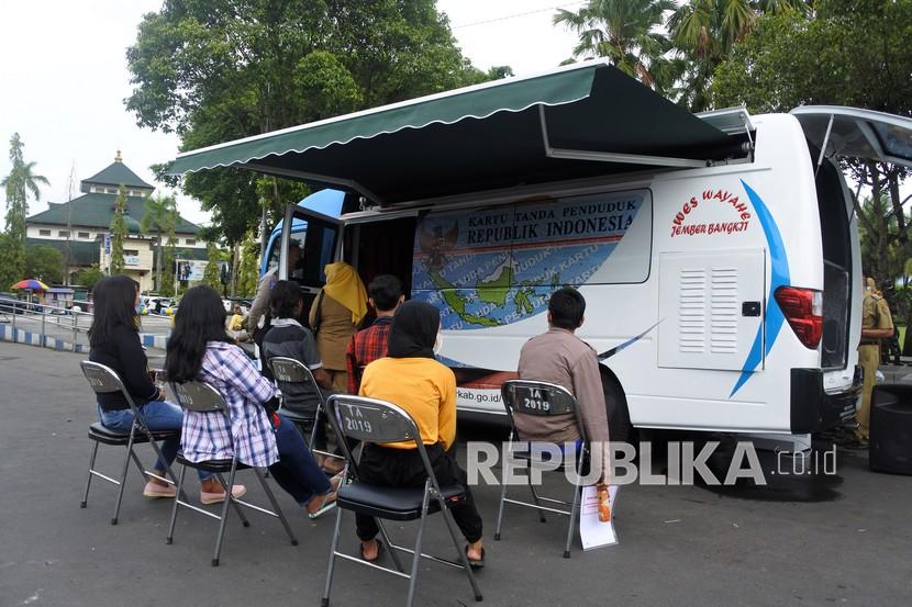 Sejumlah warga antre mengurus Administrasi Kependudukan dan Catatan Sipil (Admindukcapil) saat peluncuran mobil Admindukcapil di Alun-alun Jember, Jawa Timur, Senin (3/1/2022). Mobil pelayanan keliling Admindukcapil milik Pemkab Jember diluncurkan untuk memudahkan warga dalam pelayanan pengurusan 24 jenis administrasi.