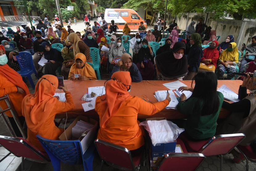 Petugas melayani warga saat penyaluran bantuan langsung tunai (BLT) minyak goreng dan bantuan program sembako di Kantor Pos Palu di Palu, Sulawesi Tengah, Kamis (14/4/2022). Pemerintah melalui PT Pos Indonesia mendistribusikan BLT minyak goreng sebesar Rp300 ribu dan bantuan sembako tunai sebesar Rp200 ribu untuk keluarga penerima manfaat dan BLT.