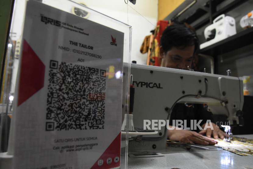 Penjahit menggunakan metode transaksi nontunai QRIS di Pasar Santa, Jakarta, Senin (6/12/2021). Kepala Kantor BI Perwakilan DKI Jakarta Onny Widjanarko mengatakan, pihaknya saat ini menargetkan pengguna Quick Response Code Indonesian Standard (QRIS) di Jakarta tembus 4,5 juta merchant.