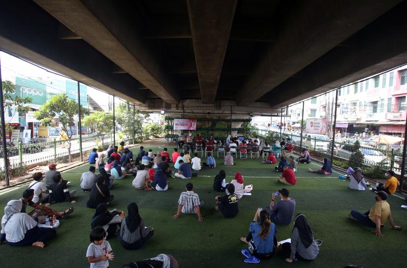 Warga mengantre duduk lesehan untuk mengikuti vaksin booster COVID-19 di bawah jembatan layang Ciputat, Tangerang Selatan, Banten, Sabtu (2/4/2022). Vaksinasi yang diselenggarakan Polri diikuti warga sekitar dan pedagang Ciputat yang berencana akan mudik lebaran.