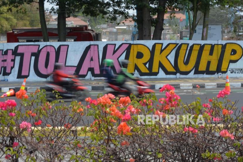Pengendara melintas di area mural Tolak RUU RKUHP di Rawamangun, Jakarta Timur, Senin (30/9/2019).