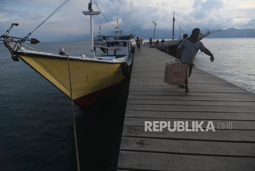 Warga membawa barang dari atas kapal yang bersandar ditambatan perahu yang dibangun dengan menggunakan dana desa di Desa Wani, Kabupaten Donggala, Sulawesi Tengah, Senin (11/4/2022). Tambatan perahu yang dibangun dengan menggunakan dana desa tersebut bermanfaat bagi masyarakat di desa tersebut yang sebagian besar menggantungkan hidupnya dari aktivitas di laut baik sebagai nelayan ataupun buruh bongkar muat angkutan kapal.