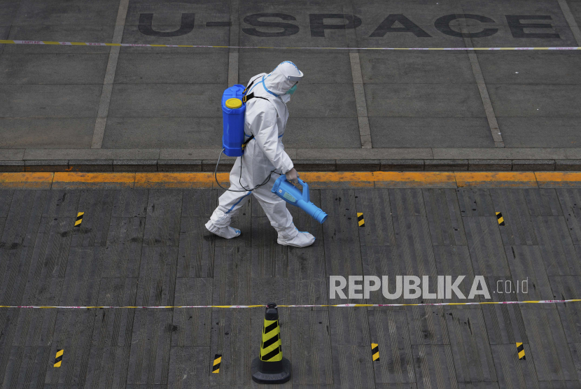 Seorang petugas kesehatan yang mengenakan alat pelindung menyemprotkan disinfektan di lokasi pengujian virus corona untuk penduduk yang dikurung pada Jumat, 29 April 2022, di Beijing.