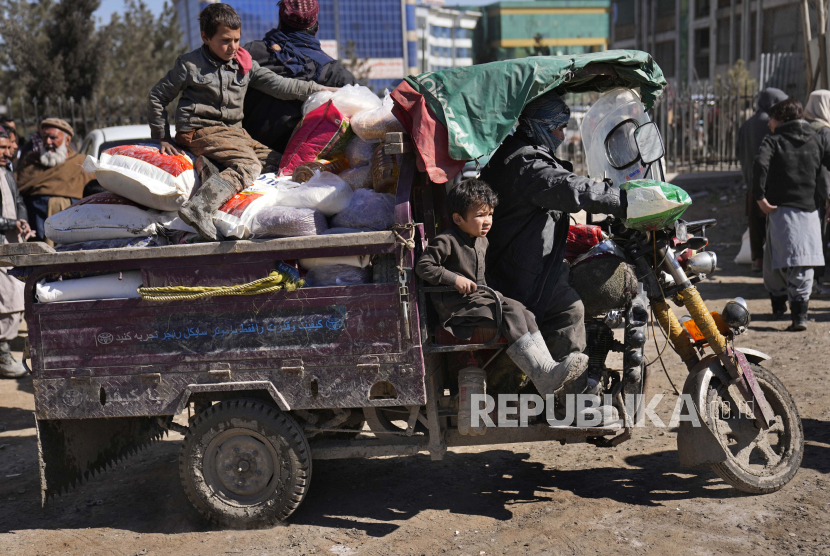 Seorang pria Afghanistan dengan anak-anaknya naik kendaraan roda tiga setelah mereka menerima pasokan makanan, selama distribusi bantuan kemanusiaan untuk keluarga yang membutuhkan, di Kabul, Afghanistan, Rabu, 16 Februari 2022. Afghanistan telah mengalami transformasi dramatis dalam setengah tahun pemerintahan Taliban. Negara ini merasa lebih aman dan tidak terlalu keras dibandingkan dalam beberapa dasawarsa, tetapi juga lebih miskin karena ekonomi yang dulunya didorong oleh bantuan menuju keruntuhan.