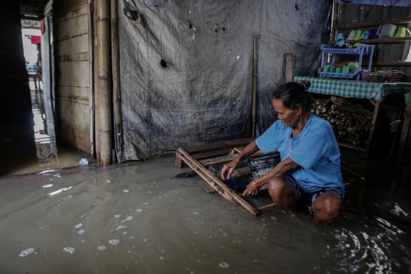 Seorang warga mencuci piring di dapur rumahnya yang terendam banjir di Pakuhaji, Kabupaten Tangerang, Banten. Sebanyak 50 kepala keluarga di Sepatan, Tangerang terdampak banjir.