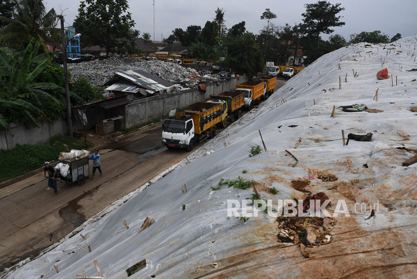 Pekerja membawa sampah menggunakan gerobak melintasi plastik yang menutup tumpukan sampah di TPA Cipayung, Depok, Jawa Barat, Jumat (6/2/2020). Dinas Lingkungan Hidup dan Kebersihan (DLHK) Kota Depok menyiagakan 40 unit truk sampah dan 125 petugas kebersihan atau pesapon selama libur lebaran 2022.