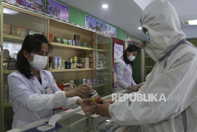 Seorang karyawan Kantor Manajemen Obat Distrik Daesong di Pyongyang memberikan obat kepada seorang penduduk saat negara meningkatkan langkah-langkah untuk menghentikan penyebaran penyakit di Pyongyang, Korea Utara, Senin, 16 Mei 2022.