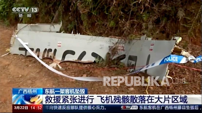 Dalam gambar yang diambil dari rekaman video yang dijalankan oleh CCTV China, polisi menutup puing-puing di lokasi kecelakaan pesawat di Kabupaten Tengxian di Daerah Otonomi Guangxi Zhuang China selatan, Selasa, 22 Maret 2022. Dompet bernoda lumpur. kartu bank. Kartu identitas resmi. Beberapa barang pribadi dari 132 nyawa yang diduga hilang dijajarkan oleh petugas penyelamat yang menjelajahi lereng gunung terpencil pada hari Selasa untuk mencari puing-puing pesawat China Eastern yang satu hari sebelumnya secara misterius jatuh dari langit dan meledak menjadi bola api besar.