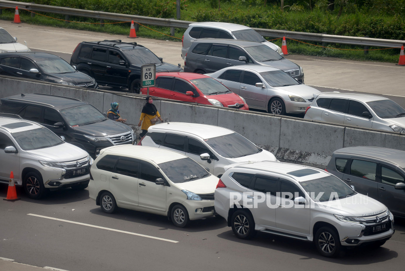 Pemudik keluar dari kendaraannya ketika terjebak kemacetan di Gerbang Tol Cikampek Utama, Purwakarta, Jawa Barat, Sabtu (30/4/2022). Pada H-2 Lebaran ini, sejumlah rekayasa lalu lintas masih diberlakukan di ruas tol trans jawa baik sistem contra flow hingga one way guna mengatasi kepadatan lalulintas. PT Jasa Marga (Persero) Tbk mencatat sebanyak 1.394.854 kendaraan meninggalkan wilayah Jabotabek pada H-10 sampai dengan H-3 Hari Raya Idul Fitri 1443 H.Prayogi/Republika