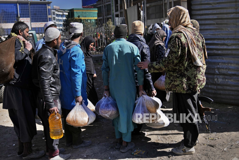 Warga Afganistan membawa persediaan makanan saat pendistribusian bantuan kemanusiaan untuk keluarga yang membutuhkan, di Kabul, Afganistan, Rabu, 16 Februari 2022. Afganistan telah mengalami transformasi dramatis dalam setengah tahun pemerintahan Taliban. Negara ini merasa lebih aman dan tidak terlalu keras dibandingkan dalam beberapa dasawarsa, tetapi juga lebih miskin karena ekonomi yang dulunya didorong oleh bantuan menuju keruntuhan.