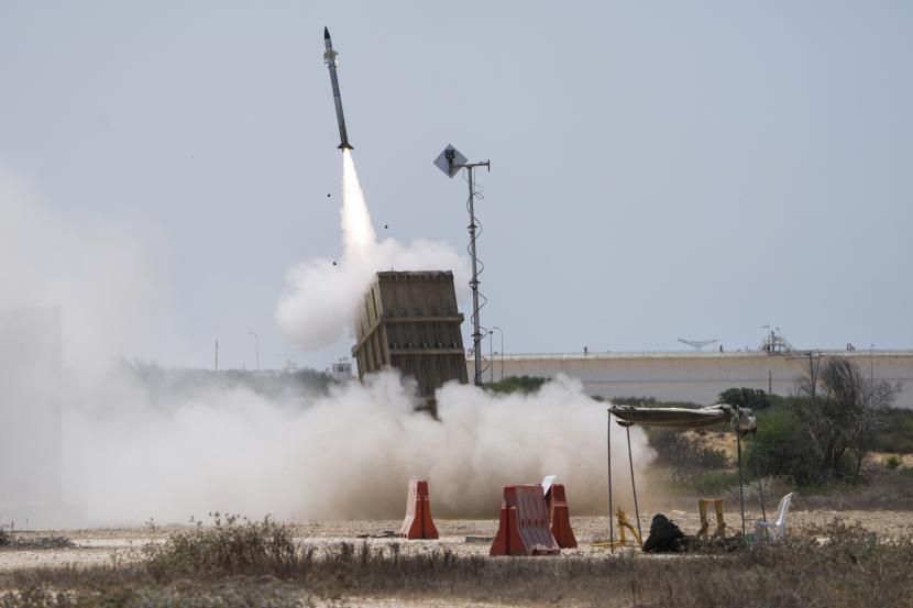 Seorang tentara Israel berlindung saat sistem pertahanan udara Iron Dome diluncurkan untuk mencegat roket yang ditembakkan dari Jalur Gaza, di Ashkelon, Israel selatan, Ahad, 7 Agustus 2022. Israel telah membunuh dua militan senior Jihad Islam dalam tiga hari penerbangan serangan di Jalur Gaza, dan militan Palestina telah meluncurkan hampir 600 roket ke Israel. Para pejabat Palestina mengatakan sedikitnya 31 orang di Gaza telah tewas.