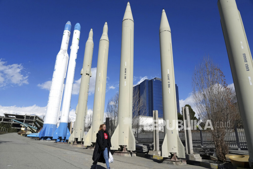 Seorang wanita berjalan melewati rudal dan pembawa satelit buatan dalam negeri Iran yang ditampilkan dalam pameran permanen di area rekreasi di Teheran utara, Iran, Jumat (3/2/2023).