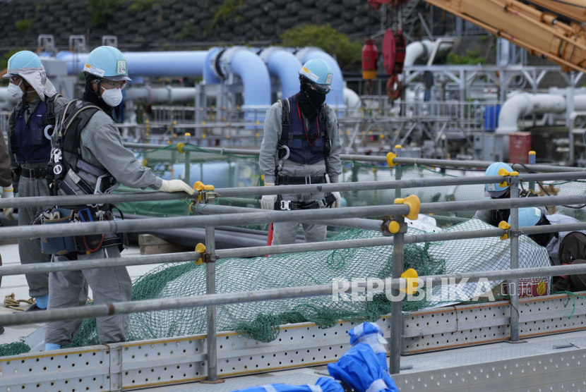 Para pekerja meletakkan material konstruksi di pembangkit listrik tenaga nuklir Fukushima Daiichi, yang dioperasikan oleh Tokyo Electric Power Company Holdingsdi kota Futaba, timur laut Jepang.