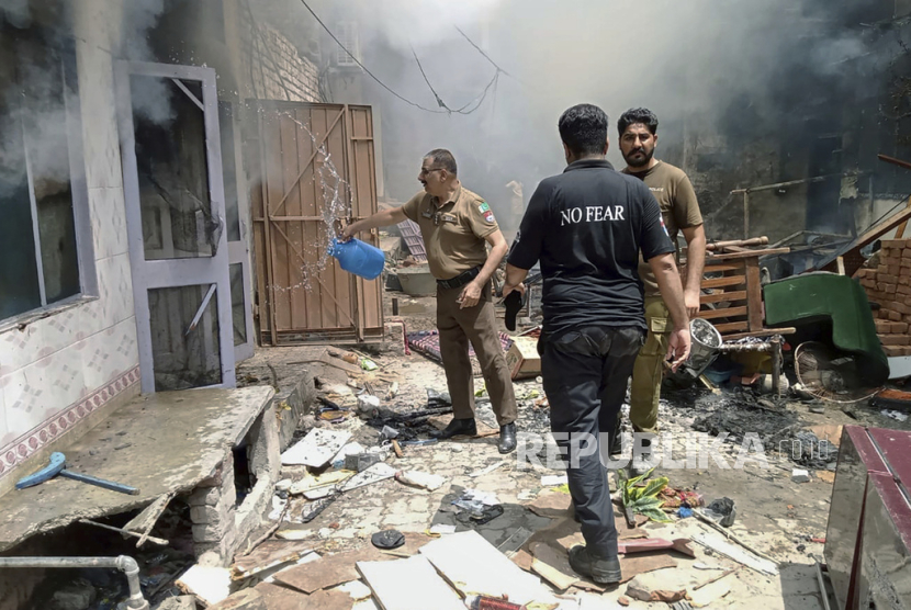 Polisi menyiramkan air ke rumah yang terbakar Jaranwala ,Pakistan, Rabu (16/8/2023).