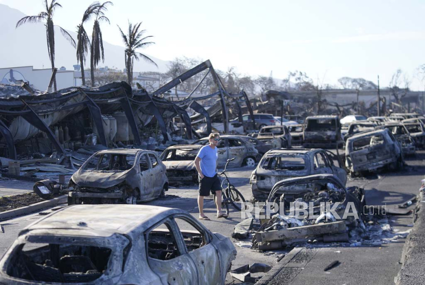 Seorang pria berjalan melewati reruntuhan kebakaran hutan di Lahaina, Hawaii, AS, Jumat, (11/8/2023).