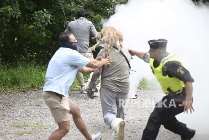 A police officer (R) stops a counter-protester (C, front) trying to put out a copy of the Koran that was set on fire by Salwan Momika (C-back), originally from Iraq, outside the Iranian Embassy in Lidingo, Stockholm, Sweden, 18 August 2023.