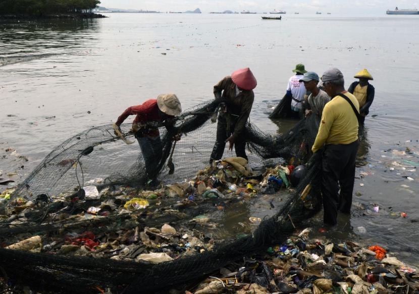Nelayan membersihkan sampah yang tersangkut di jaring saat melaut di Pantai Sukaraja, Bandar Lampung, Lampung, Selasa (25/10/2022). Warga dan nelayan sekitar mengeluhkan limbah sampah rumah tangga yang terbawa arus sungai sampai ke pantai sehingga membuat hasil tangkapan para nelayan berkurang dan membuat lingkungan pantai menjadi kotor.